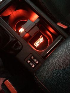 the interior of a car with red lights and black leather trim, including an automatic gear box