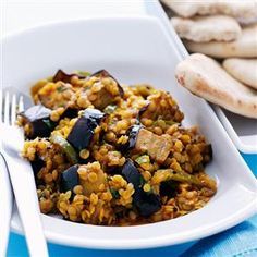 a white bowl filled with rice and eggplant on top of a blue table