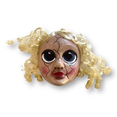 a creepy doll head with blonde hair and big eyes on a white background for decoration