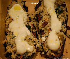 two stuffed eggplant halves are covered with rice and other toppings in a baking dish