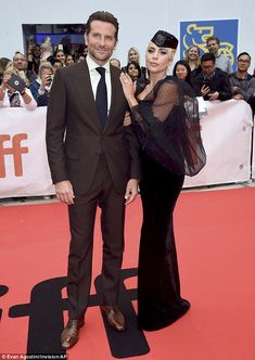 a man and woman standing on top of a red carpet next to each other in front of a crowd