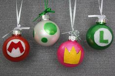 four christmas ornaments with the letter l painted on one ornament, each decorated in different colors