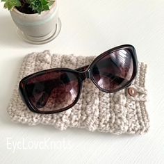 a pair of sunglasses sitting on top of a knitted case next to a potted plant