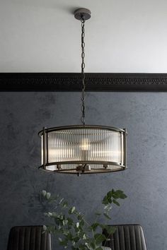 a chandelier hanging from the ceiling over a dining room table with two chairs and a potted plant