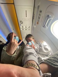 two people are sitting on an airplane with masks