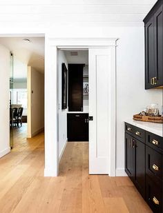 an empty kitchen with black cabinets and wood flooring in the center, along with white walls