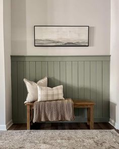 a wooden bench sitting in the corner of a room next to a painting on the wall