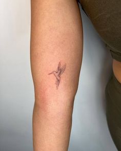 a woman's arm with a small tattoo of a hummingbird on the left thigh