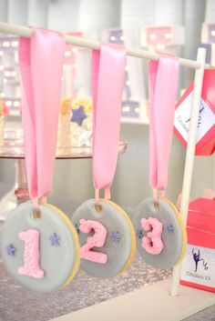 three decorated cookies hanging from a rack with pink and blue ribbons on it's sides