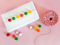 candy and lollipops on a pink surface next to a roll of twine