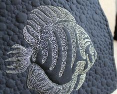 a close up view of a black and white pillow with an intricate fish design on it