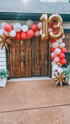 the entrance to a house decorated with balloons and streamers that spell out the number thirteen