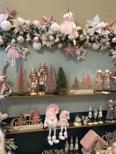 christmas decorations are displayed on shelves in a store display case, with pink and white ornaments hanging from the ceiling