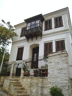 a white house with black shutters on the front and second story, surrounded by stone steps