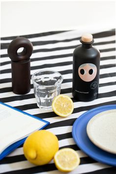 a table topped with plates and glasses next to lemons on top of a black and white striped table cloth