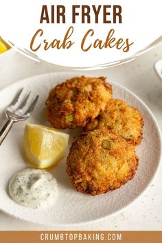 two crab cakes on a white plate with lemon wedges