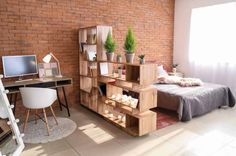 a bed room with a neatly made bed next to a brick wall and a computer desk