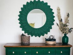 a green dresser with a mirror and vase on top