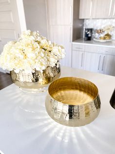 two vases filled with white flowers sitting on top of a counter