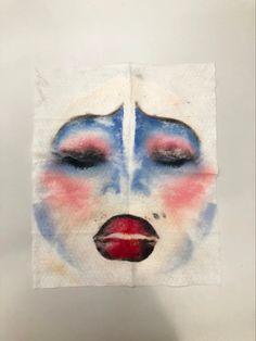 a piece of paper with a painting of a woman's face and red lips