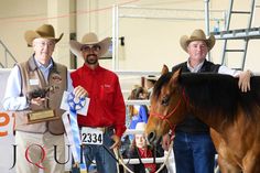 three men standing next to each other with horses in front of them and one man holding an award