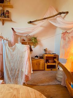 a room with some clothes hanging from the ceiling and other items on the table in front of it