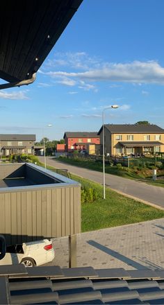 a car is parked in front of some houses on the side of a road with other buildings behind it