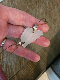 a person's hand with two rings and a small piece of glass on it