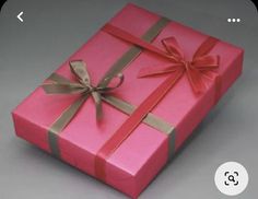 a pink gift box with gold ribbon and bow