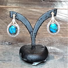 "A pair of oval blue turquoise cabochons veined with copper are set in bezels surrounded by diamond halos in 14k white gold. The earring tops are diamond-studded yellow gold fleur-de-lis shapes. The earring measures about 28mm (or a little over 1\") long by 16mm (about 5/8\") wide. The earrings are soldered to 14k gold posts with friction backs. Upgrade to locking Protektor backs for just $50 more. Turquoise Dimensions11x9mm EnhancementNatural ColorMedium to light blue; copper matrix Cut Good Po Bezel Set Cabochon, Mystic Topaz Earrings, Gold Filigree Earrings, Bridesmaid Earrings Gold, Cobalt Blue Earrings, Halo Diamond Earrings, White Sapphire Engagement Ring, Blue Dangle Earrings, Gold Leaf Earrings