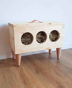 a wooden box with three holes in it sitting on the floor next to a wall