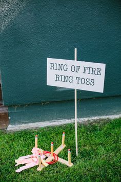 a sign that says ring of fire ring toss on top of matches in the grass