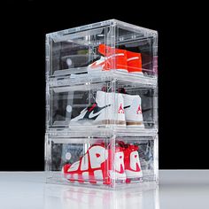 three clear acrylic boxes with red and white shoes in them