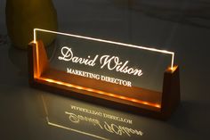 a lighted business card holder on a table with a vase in the background and a light up sign that reads, david wilson marketing director