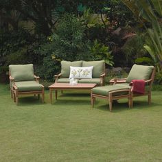 the lawn is full of green grass and wooden furniture with pillows on top of them