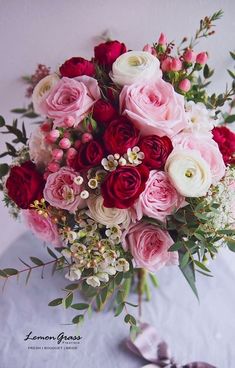 a bouquet of pink and red flowers sitting on top of a white cloth covered table