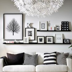 a white couch sitting under a chandelier in a living room next to pictures