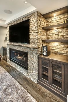 a living room with a large stone fireplace and built in entertainment center next to a flat screen tv