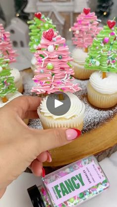 someone is decorating cupcakes with pink and green frosting on a tray