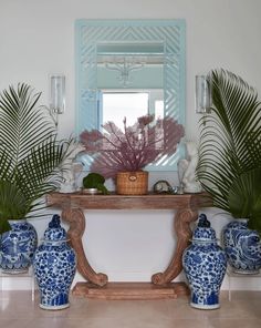 blue and white vases sitting on top of a wooden table next to a mirror