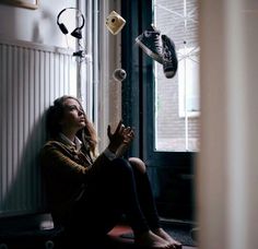 a woman sitting on the floor in front of a window with headphones hanging from her ears