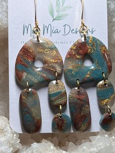 These adorable abstract earrings are handcrafted using translucent polymer colored with blue, rust with added gold leafing to create a one-of-a-kind pair of earrings.  Assembled using gold embellishments, these earrings are both lightweight and hypoallergenic. Artsy Resin Dangle Earrings, Artsy Resin Drop Earrings, Artsy Blue Dangle Earrings, Bohemian Gold Resin Earrings, Artsy Resin Earrings With Ear Wire, Unique Resin Dangle Earrings, Unique Dangle Resin Earrings, Artsy Blue Teardrop Earrings, Handmade Turquoise Resin Earrings