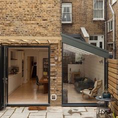 an open glass door leading to a living room and dining area in a brick building