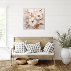 a living room with white walls and wooden flooring is decorated in neutral tones, including an abstract floral painting on the wall