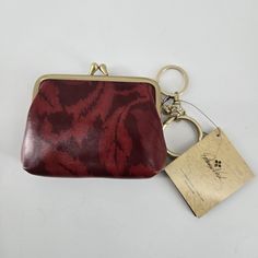 a red and black purse sitting on top of a white table next to a keychain