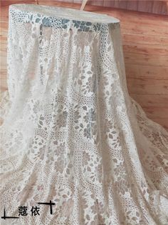 a white lace curtain hanging on a wooden wall next to a window with chinese writing