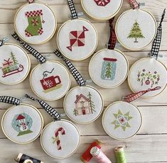 cross - stitch christmas ornaments are arranged on a table with thread and spools