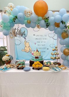 a winnie the pooh birthday party with balloons and desserts