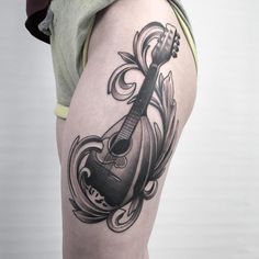 a woman with a guitar tattoo on her thigh