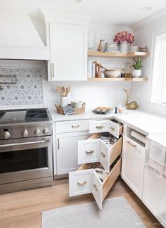 a kitchen with white cabinets and open drawers